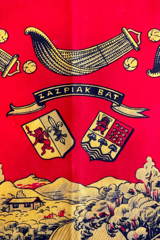 Bright red and yellow “Zazpiak Bat” scarf featuring the Basque coat of arms. The seven Basque provinces, which are represented in detailed illustrations in red, black, and yellow.