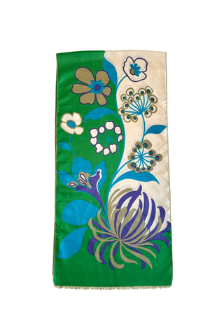 A vintage 1960s scarf by designer Jean Dessès made of silk twill, with a large colourblock grass green and cream background, with a large stylized floral print featuring approximately six large different types of flowers in combinations of turquoise blue, indigo, cream, and beige colours. The name of the designer Jean Dessès is printed at the bottom right of the long rectangular scarf.