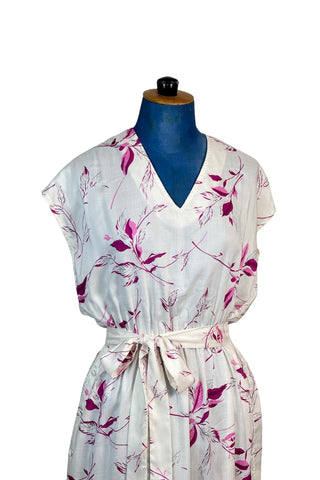 Vintage 1970s V-neck dress of soft woven rayon with an elegant botanical print in magenta and fuchsia. Adorable button trim down both sides of the skirt, with a curved hem. The waist is elasticized, giving a “blouson” effect to the bodice. Includes a matching sash belt.