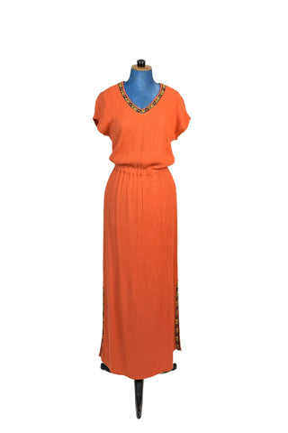 Vintage 1970s orange maxi dress with V-neck  in textured rayon crepe. There are slits on both sides of the skirt. The neckline and side slits are adorned with floral embroidered trim. The waist is elasticized. The dress is unlined. 