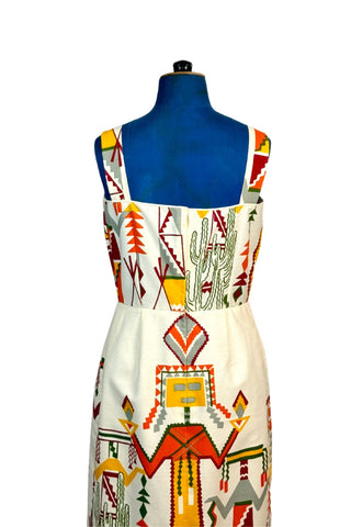 Incredible vintage 1960s sheath dress with giant Native American Kachina doll and cactus motif on medium-weight cotton. The top of the bodice is finished with cream piping. The skirt is lined in beige acetate, while the bodice is unlined. Closes with a nylon zipper.