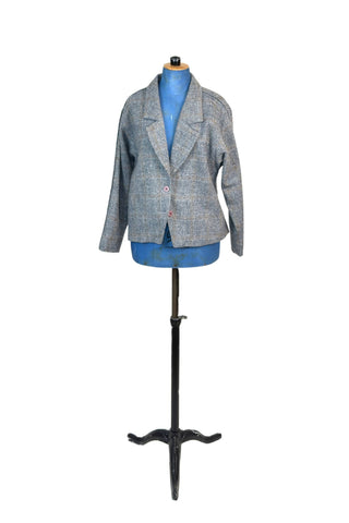 Vintage late 1970s, early 1980s grey wool blazer jacket in 100% pure new wool. The windowpane tweed weave has a subtle pattern in shades of blue, yellow, and gold. Closes with two salmon pink buttons. Fully lined in pink acetate. 