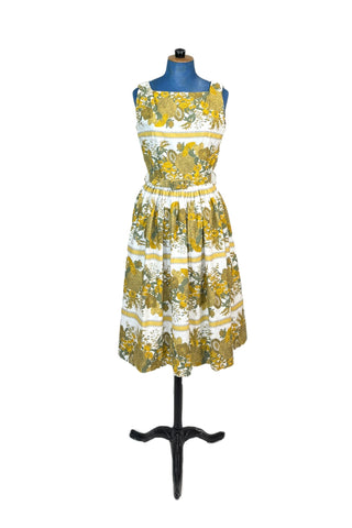 Vintage 1950s cotton day dress with an sunny yellow and green floral print. Sleeveless with a square neckline and gathered waist, the dress includes a matching self-fabric belt. Perfect for a splendid summer picnic, tea party, or a stroll through the botanical gardens.