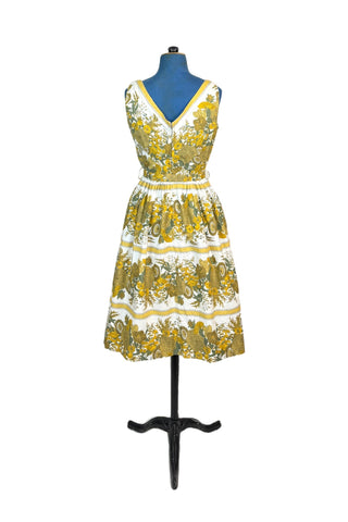 Vintage 1950s cotton day dress with an sunny yellow and green floral print. Sleeveless with a square neckline and gathered waist, the dress includes a matching self-fabric belt. Perfect for a splendid summer picnic, tea party, or a stroll through the botanical gardens.