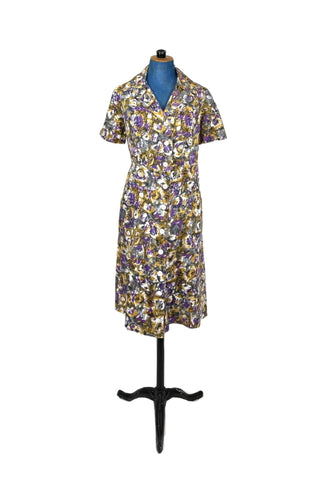 Lovely vintage day dress in abstract purple and yellow floral. Closes with nine white buttons down the front. The medium-weight cotton fabric has a subtle ribbed texture.