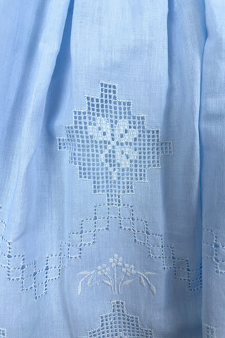 Intricately embroidered linen little girls’ dress with geometric floral openwork embroidery featured on the centre front of the pleated skirt. The front hem is heavily embroidered with a wide zig-zag panel of geometric and floral openwork embroidery.