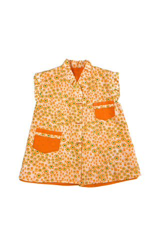 Bright tangerine orange reversible vintage 1960s girls’ vest with orange and green floral print. Each reversible side has pockets trimmed in the reverse-side fabric. The neckline and sleeve holes are trimmed with self-fabric ruffles.