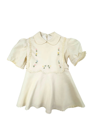 This darling vintage 1960s cape and dress set is embroidered with pink cherry blossoms and pink, blue and yellow tulips. The cape has a detachable hood which attaches with buttons at the back and sides of the cape’s round Peter Pan collar. The collar and hem of the cape are trimmed with scalloped crocheted lace. The cape has a double-breasted front closure with white and silver tone square buttons. There are arm holes in the middle of the front seams.