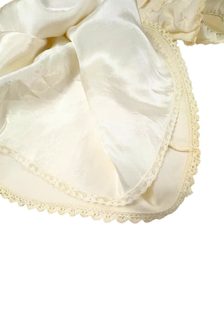 This darling vintage 1960s cape and dress set is embroidered with pink cherry blossoms and pink, blue and yellow tulips. The cape has a detachable hood which attaches with buttons at the back and sides of the cape’s round Peter Pan collar. The collar and hem of the cape are trimmed with scalloped crocheted lace. The cape has a double-breasted front closure with white and silver tone square buttons. There are arm holes in the middle of the front seams.