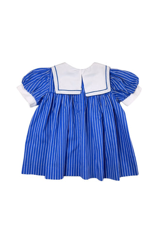 Adorable vintage 1980s toddler sailor dress with separate blue and white striped under-dress and white bib-collar pinafore apron which closes in the back with blue and white buttons. The sailor collar of the dress is embroidered with two anchors and finished with a bright red bow tie, while the pinafore has a matching blue stripe around the hem. The dress closes in the back with two buttons.