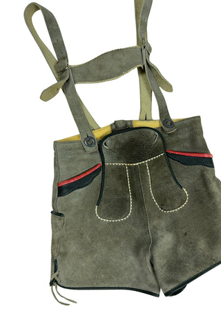 Vintage 1960s boys’ lederhosen in grey leather suede, with white scalloped suede trim, black leather accents and red suede piping.
The straps have metal buckle closures at the chest, and attach to the shorts with buttons (the shorts may be worn without straps). The front of the shorts has a flap that closes with two buttons at the waist.
In good vintage condition, with normal wear to the suede consistent with age. The inside of the front panel has a faux leather (vinyl) lining, where the vinyl has...