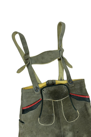 Vintage 1960s boys’ lederhosen in grey leather suede, with white scalloped suede trim, black leather accents and red suede piping.
The straps have metal buckle closures at the chest, and attach to the shorts with buttons (the shorts may be worn without straps). The front of the shorts has a flap that closes with two buttons at the waist.
In good vintage condition, with normal wear to the suede consistent with age. The inside of the front panel has a faux leather (vinyl) lining, where the vinyl has...