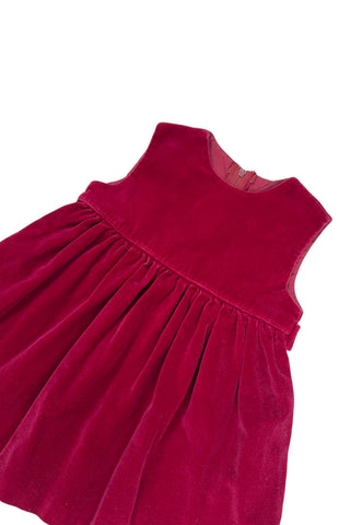 Vintage red velvet baby dress with a belted back. Sleeveless, with a simple round neckline. The high, gathered waist is trimmed with matching red piping. The thick cotton velvet dress has a fully lined bodice and unlined skirt.