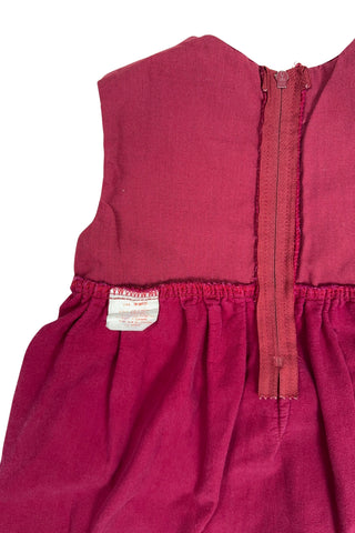 Vintage red velvet baby dress with a belted back. Sleeveless, with a simple round neckline. The high, gathered waist is trimmed with matching red piping. The thick cotton velvet dress has a fully lined bodice and unlined skirt.