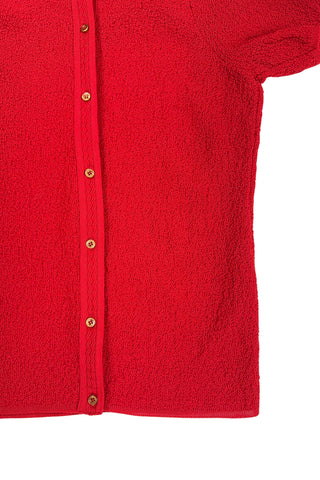 Vintage 1960s cardigan sweater in bright red ‘crazy’ textured knit (see closeup). The sweater features short sleeves with a round, ribbed collar, and a button placket with a zigzag pattern. The tight knit stitch gives the sweater a structured, weighty feel. The material feel like an acrylic blend.