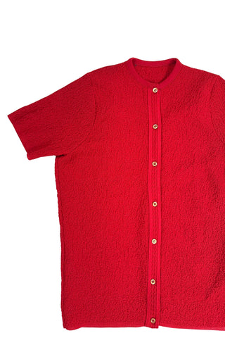 Vintage 1960s cardigan sweater in bright red ‘crazy’ textured knit (see closeup). The sweater features short sleeves with a round, ribbed collar, and a button placket with a zigzag pattern. The tight knit stitch gives the sweater a structured, weighty feel. The material feel like an acrylic blend.