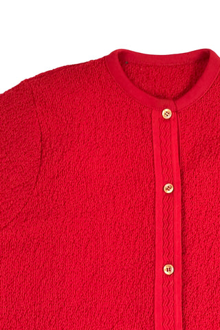 Vintage 1960s cardigan sweater in bright red ‘crazy’ textured knit (see closeup). The sweater features short sleeves with a round, ribbed collar, and a button placket with a zigzag pattern. The tight knit stitch gives the sweater a structured, weighty feel. The material feel like an acrylic blend.