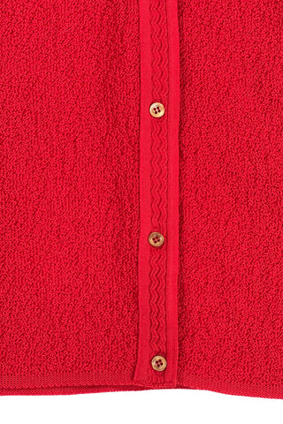Vintage 1960s cardigan sweater in bright red ‘crazy’ textured knit (see closeup). The sweater features short sleeves with a round, ribbed collar, and a button placket with a zigzag pattern. The tight knit stitch gives the sweater a structured, weighty feel. The material feel like an acrylic blend.