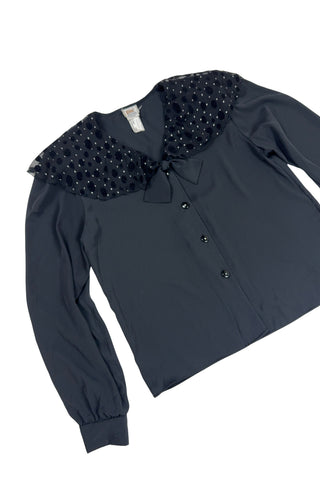 Vintage 1980s sheer black blouse with a chiffon collar featuring velvet polkadots and dots of silver sparkles. The blouse closes with four black buttons with rhinestone centres. The cuffs have matching button closures. The blouse comes with a separate tie piece that can be tied around the neck, or left off for a different look.