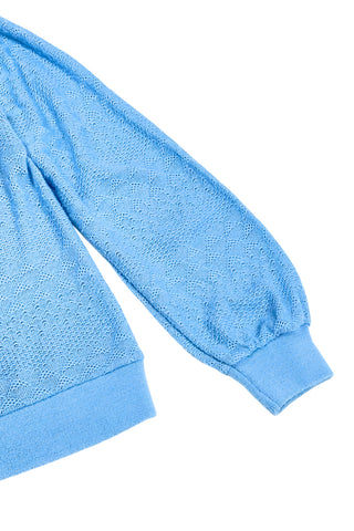 Vintage 1970s blue cardigan sweater with detailed eyelet knit in a variety of different stitches. Features a Peter Pan collar, clear plastic buttons, and ribbed sleeve cuffs and waistband, similar to a sweatshirt.

Designed by Excelsior Knitting Mills. Made in Canada.