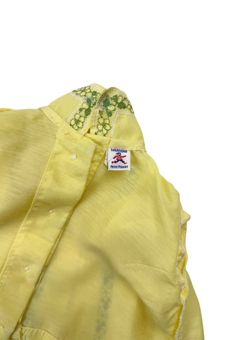Vintage 1960s baby blouse top in sunshine yellow with accents of green and white lace. The top has three wide box pleats across the chest, with a small pointed collar, and short puffed sleeves. The top has a button closure down the back.

Designed by Creations Petit Poucet.