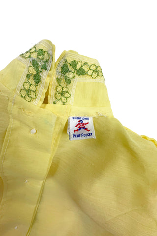Vintage 1960s baby blouse top in sunshine yellow with accents of green and white lace. The top has three wide box pleats across the chest, with a small pointed collar, and short puffed sleeves. The top has a button closure down the back.

Designed by Creations Petit Poucet.