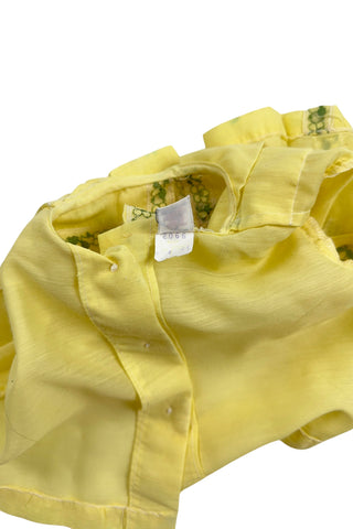Vintage 1960s baby blouse top in sunshine yellow with accents of green and white lace. The top has three wide box pleats across the chest, with a small pointed collar, and short puffed sleeves. The top has a button closure down the back.

Designed by Creations Petit Poucet.