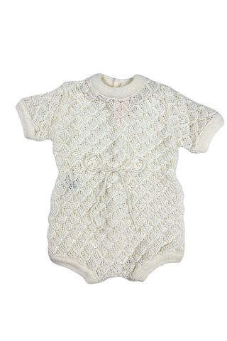 Vintage 1960s baby onesie bodysuit of cream crochet knit in a textural layered petal stitch. This beautiful and special piece would be perfect for baby’s layette.

Features a cord tie at the waist, which ties in a bow. The onesie closes in the back with five buttons up the back, and also has snap closures at the bottom.

Designed by Renzo. Made in Italy.