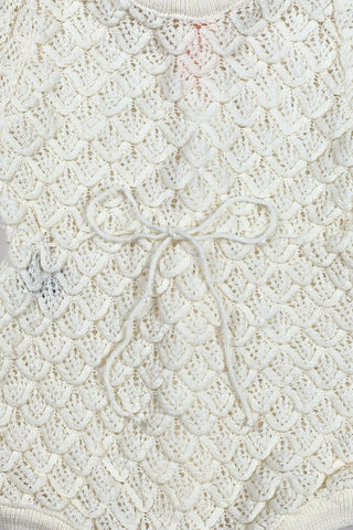 Vintage 1960s baby onesie bodysuit of cream crochet knit in a textural layered petal stitch. This beautiful and special piece would be perfect for baby’s layette.

Features a cord tie at the waist, which ties in a bow. The onesie closes in the back with five buttons up the back, and also has snap closures at the bottom.

Designed by Renzo. Made in Italy.