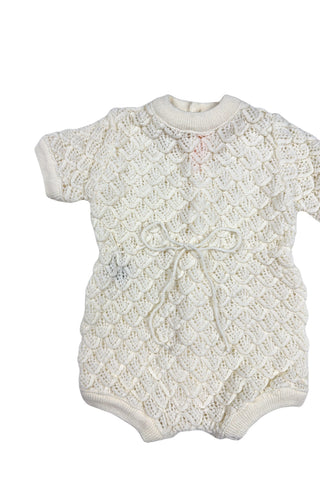 Vintage 1960s baby onesie bodysuit of cream crochet knit in a textural layered petal stitch. This beautiful and special piece would be perfect for baby’s layette.

Features a cord tie at the waist, which ties in a bow. The onesie closes in the back with five buttons up the back, and also has snap closures at the bottom.

Designed by Renzo. Made in Italy.