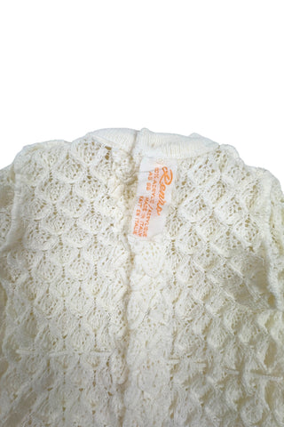 Vintage 1960s baby onesie bodysuit of cream crochet knit in a textural layered petal stitch. This beautiful and special piece would be perfect for baby’s layette.

Features a cord tie at the waist, which ties in a bow. The onesie closes in the back with five buttons up the back, and also has snap closures at the bottom.

Designed by Renzo. Made in Italy.