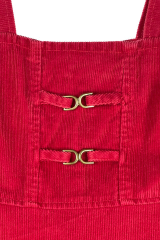 Vintage 1970s girls’ jumper dress in red cotton corduroy with decorative gold buckles across the bodice. Features a classic A-line silhouette with wide shoulder straps.

Designed by Encore. Made in Canada.

85% cotton, 15% polyester.