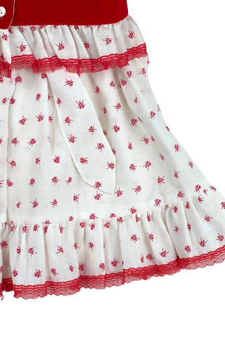 Vintage 1970s baby dress set with insect print. The set includes a dress, matching bloomers, and a red velvet vest with a peplum ruffle. The dress has short, puffed sleeves, a round neckline, and a gathered, full skirt with a back sash bow tie. The collar, cuffs, and hem are trimmed with delicate red lace. 

The dress and vest both close in the back with three pearly buttons.