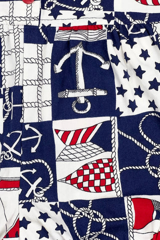 Vintage 1980s baby onesie ‘bubble’ romper in a cotton nautical print. Accented with navy trim around the collar and arm openings, and finished with three red buttons down the chest. Closes with three red buttons on the bottom.