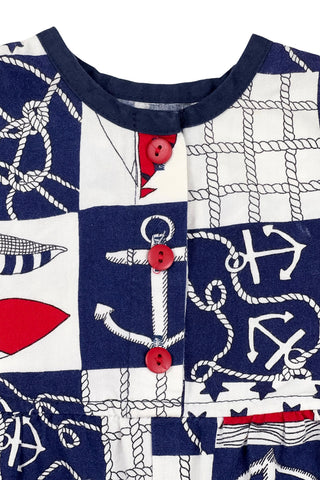 Vintage 1980s baby onesie ‘bubble’ romper in a cotton nautical print. Accented with navy trim around the collar and arm openings, and finished with three red buttons down the chest. Closes with three red buttons on the bottom.