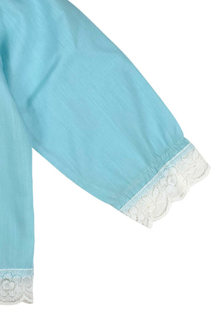 Vintage 1960s toddler blouse in blue cotton/poly blend with wide white lace down the button placket, and at the collar, cuffs, and hem.

Closes in the front with four ivory coloured buttons.