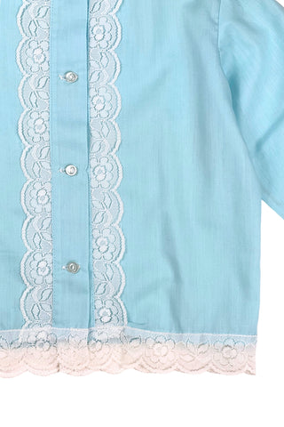 Vintage 1960s toddler blouse in blue cotton/poly blend with wide white lace down the button placket, and at the collar, cuffs, and hem.

Closes in the front with four ivory coloured buttons.