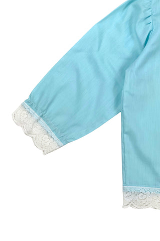 Vintage 1960s toddler blouse in blue cotton/poly blend with wide white lace down the button placket, and at the collar, cuffs, and hem.

Closes in the front with four ivory coloured buttons.