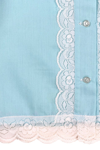 Vintage 1960s toddler blouse in blue cotton/poly blend with wide white lace down the button placket, and at the collar, cuffs, and hem.

Closes in the front with four ivory coloured buttons.