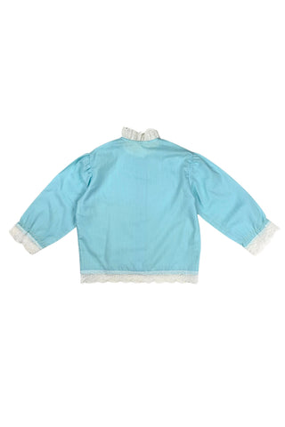 Vintage 1960s toddler blouse in blue cotton/poly blend with wide white lace down the button placket, and at the collar, cuffs, and hem.

Closes in the front with four ivory coloured buttons.