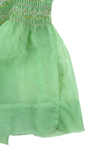 Vintage 1950s smocked baby dress in sheer light green gauze, with pink and white smocking stitching. The dress features a Peter Pan collar, puffed sleeves, and closes in the back with four lucite pink sparkle buttons. The collar and sleeves are trimmed with pink zigzag stitch.

The dress is in good vintage condition, with some areas where the seem has separated, which could be easily fixed.