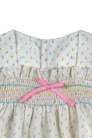 This vintage cotton baby dress is sleeveless and features smocking across the chest, and is accented with a small pink bow. The dress closes in the back with four ivory buttons.

Condition note: There is some light yellow general staining on the chest, but it is very subtle, and could likely be removed with stain treatment.