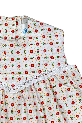 Vintage 1960s toddler girls’ white sleeveless dress featuring a red, yellow, and green floral pattern with white eyelet lace trim.

Made in Austria.