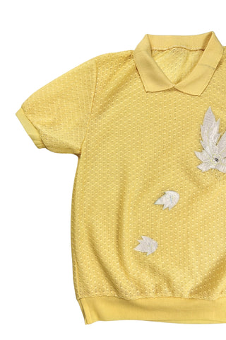 Vintage 1980s short sleeve sweater with ribbed collar and cuffs in sunny yellow tiny eyelet knit with a white leaf appliqué accented with a rhinestone center.
