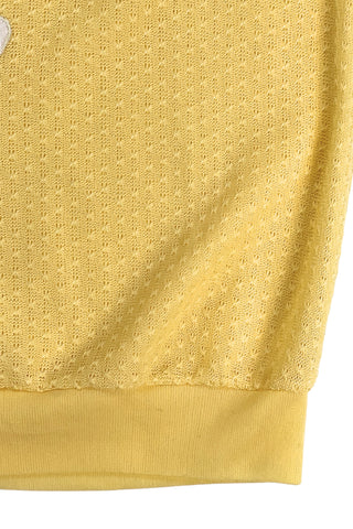 Vintage 1980s short sleeve sweater with ribbed collar and cuffs in sunny yellow tiny eyelet knit with a white leaf appliqué accented with a rhinestone center.