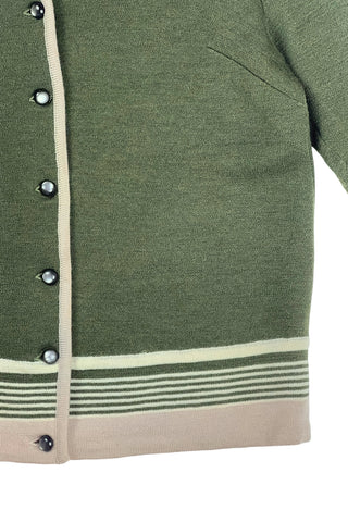 Vintage 1950s wool cardigan sweater in olive green and cream with three-quarter length sleeves. The sweater features a rolled collar with a striped design, with a matching striped band at the waist. Closes with six green lucite buttons.