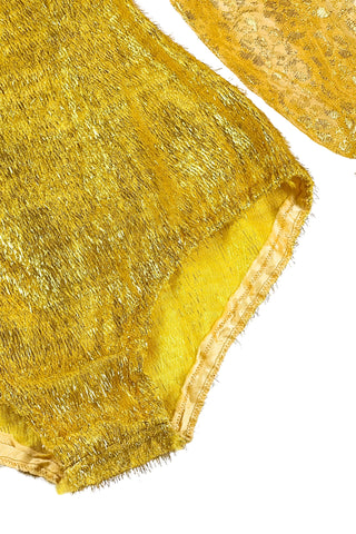 Vintage 1960s gold fringe bodysuit costume with long cuffed sheer lace sleeves and a sweetheart neckline. The hourglass cut of the non-stretch gold material keeps all your curves in place in a classic bombshell shape.

The costume closes in the back with a long cotton twill zipper. There is no opening at the bottom. The long sleeves close with hook and eye closures instead of buttons.