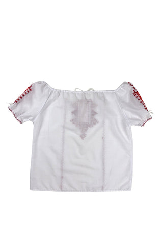 Vintage 1970s peasant blouse in white cotton with red hand embroidery stitching and red and white floral appliqué embroidered patches on the chest and sleeves. The neckline and sleeves are gathered with tiny white cord drawstring. The edges of the sleeves are trimmed with red blanket stitch.