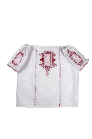 Vintage 1970s peasant blouse in white cotton with red hand embroidery stitching and red and white floral appliqué embroidered patches on the chest and sleeves. The neckline and sleeves are gathered with tiny white cord drawstring. The edges of the sleeves are trimmed with red blanket stitch.