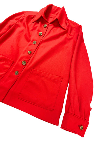 Vintage 1970s tomato red button down shirt, with a pointed collar, long sleeves, and two square patch pockets. The shirt closes with six gold textured buttons down the front, and two matching smaller buttons at the sleeve cuffs.
